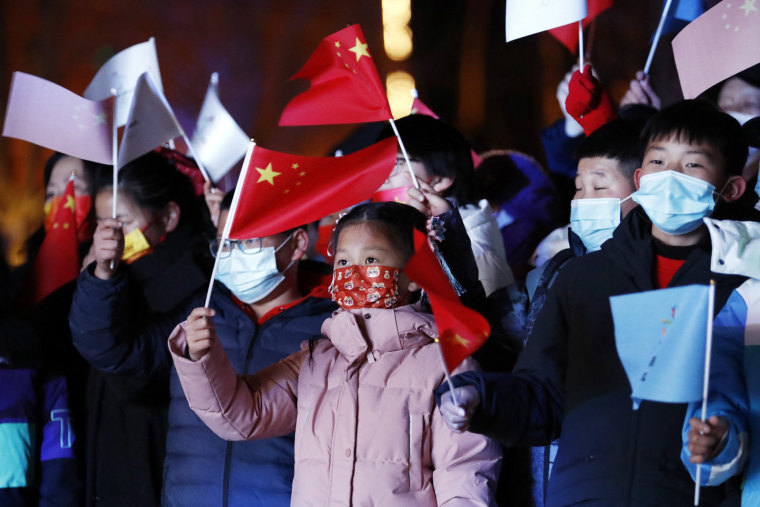 Image: Spectators wave Chinese flags during an event before the Beijing 2022 Winter Olympics opening ceremony, in Beijing