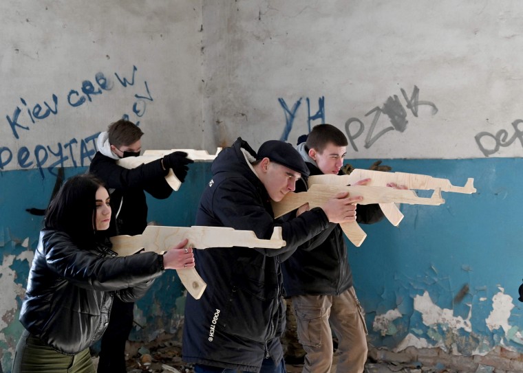 Image: Civilians hold wooden replicas of Kalashnikov rifles during a  training session in Kyiv.