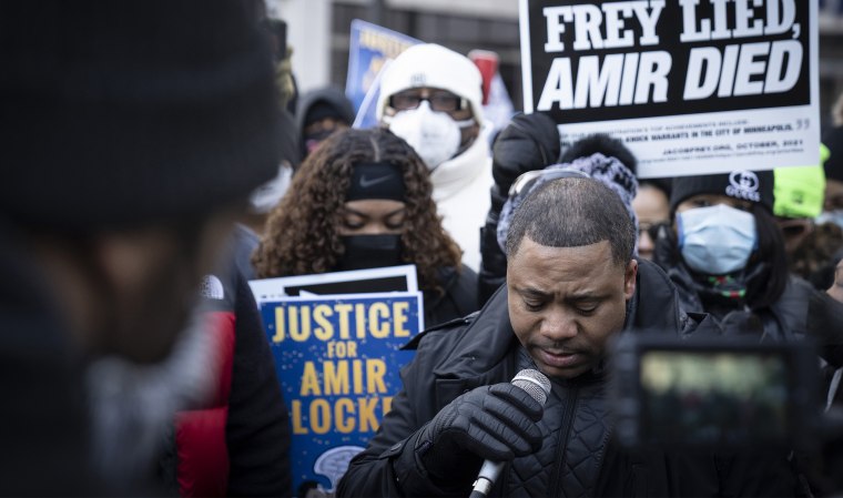 Image: Andre Locke, father of Amir Locke speaking to a crowd holding signs that read,\"Frey lied Amir died\" and \"Justice for Amir Locke\".