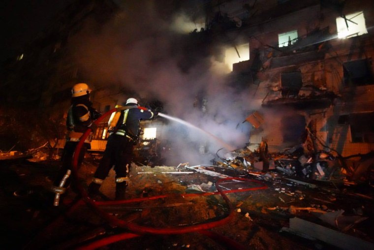 Image: Firefighters work to put out a residential building fire after debris or an explosive device from a downed Russian aircraft hit it, in Kyiv, Ukraine on Feb. 25, 2022.