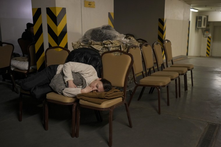 Image: A woman sleeps on chairs in the underground parking lot of a hotel that was turned into a bomb shelter in Kyiv on Feb. 27, 2022.