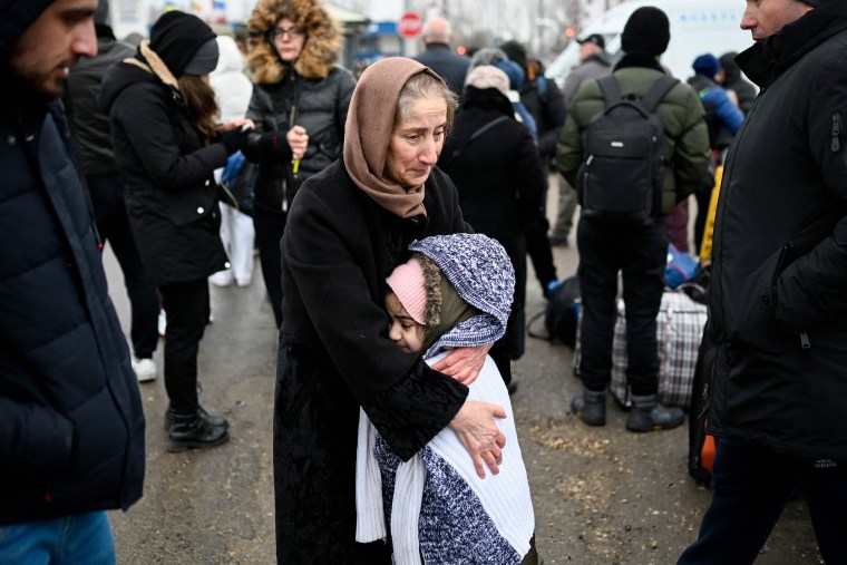 Image: A woman hugs a girl as refugees from Ukraine wait for a transport at the Moldova-Ukrainian border's checkpoint near the town of Palanca on Tuesday.