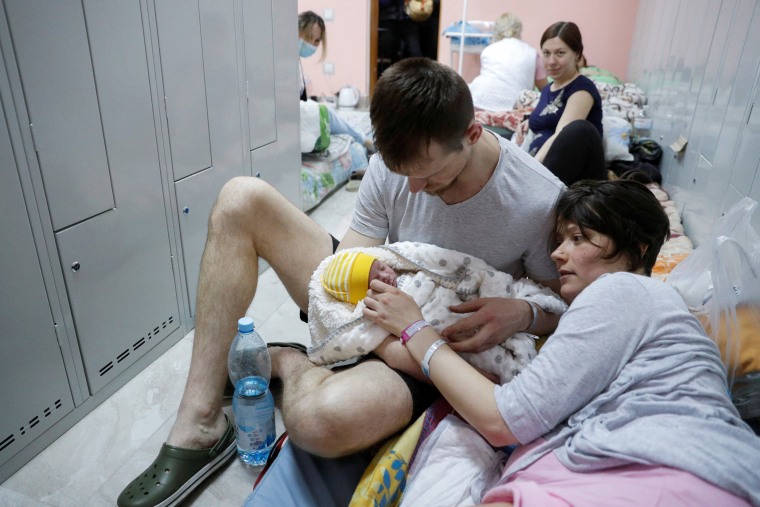 Image: A couple with their newborn baby take shelter in the basement of a perinatal centre as air raid siren sounds are heard amid Russia's invasion of Ukraine, in Kyiv