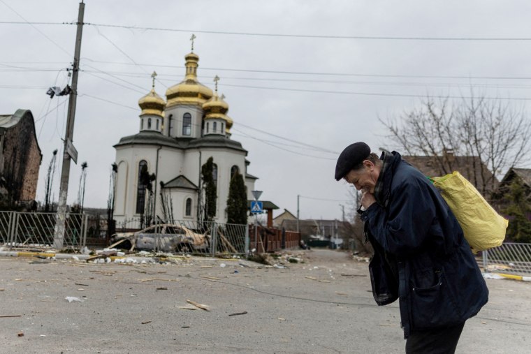 Image: A man takes a pause as he evacuates from the town, on the only escape route used by locals after days of heavy shelling, while Russian troops advance towards the capital, in Irpin, near Kyiv