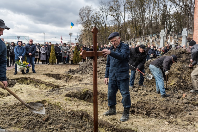 Men dig graves for Ukrainian soldiers Ivan Koverznev and Viktor Dudar, who were both killed on March 2 in the war launched by Russia, at Lychakiv Cemetery in Lviv on Tuesday.