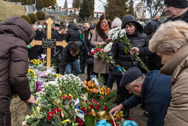 Family members and friends put flowers on the grave of a Ukrainian soldier Ivan Koverznev at Lychakiv Cemetery in Lviv on Tuesday.
