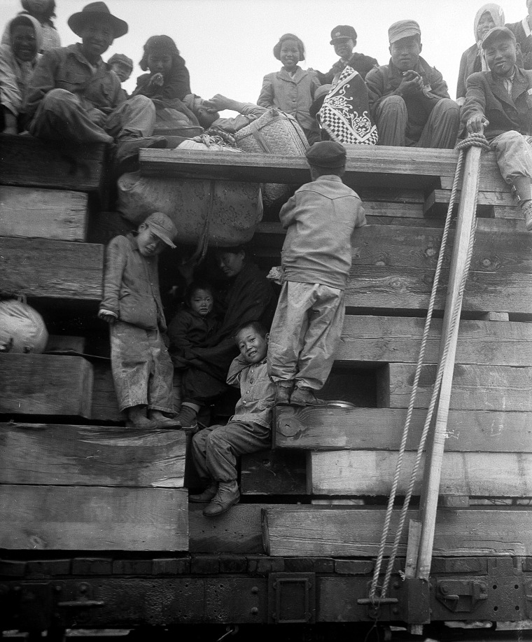 Image: A South Korean family manages to squeeze into an open spot between this train's lumber cargo as they join the exodus from the Seoul area during a stop at Anyang, South Korea, on April 28, 1951.
