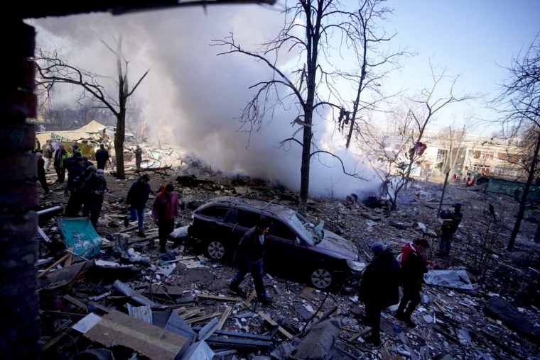 Civilians gather outside a residential building damaged by shelling in Kyiv, in this handout picture released Friday.