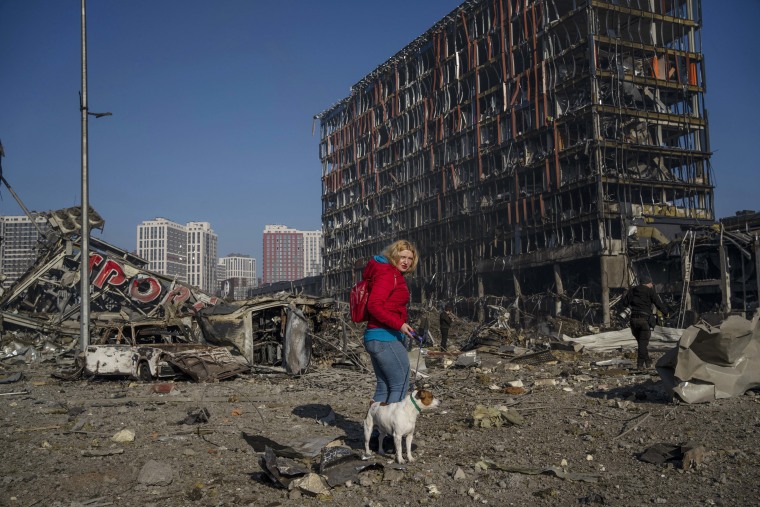 Irina Zubchenko walks with her dog Max amid the destruction caused after shelling of a shopping center, in Kyiv, Ukraine, on Monday.