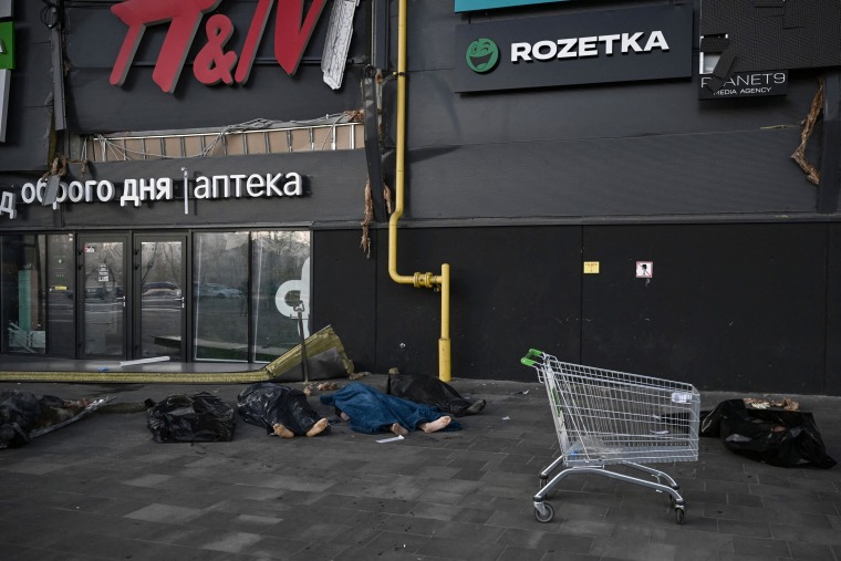 Bodies of Ukrainian servicemen are covered with blankets and plastic bags outside the Retroville shopping center following a Russian missile attack in Kyiv on Monday.
