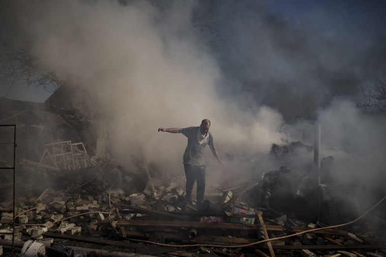 A man walks on the debris of a burning house, destroyed after a Russian attack in Kharkiv, Ukraine, on Thursday.