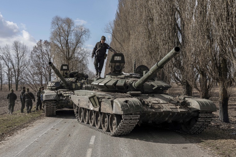 A Ukrainian serviceman stands atop a captured Russian tank after fighting with Russian troops in the village of Lukyanivka outside kyiv on Sunday.