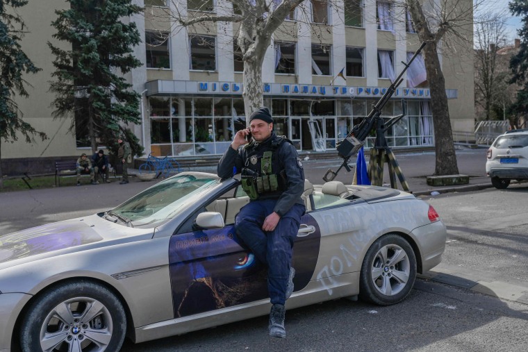 A Ukrainian police officer sits on a sports car fitted with a heavy machine gun on the back in Mykolaiv, Tuesday.