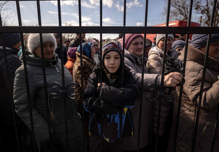Ukrainian residents wait for food outside a church in the northeastern city of Trostianets, on March 29, 2022.