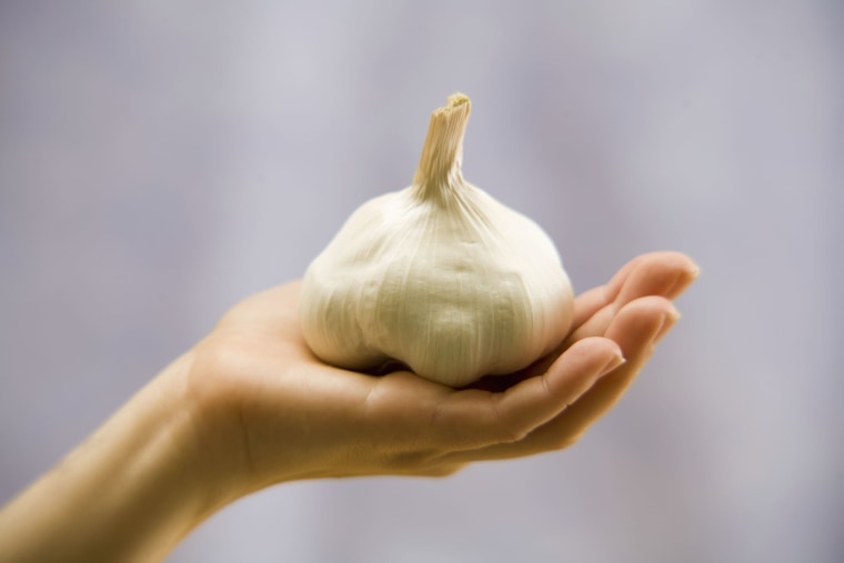 Woman holding garlic bulb, close-up