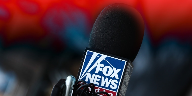 Photo illustration: Red color overlay over an image of a microphone with the Fox News logo.