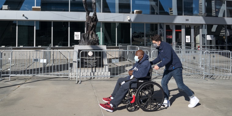 Image: A voter on a wheelchair being assisted during early voting for the Georgia runoff elections at the State Farm Arena in Atlanta, Georgia.