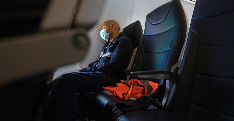 Image: A passenger wearing a protective mask sleeps during a flight.