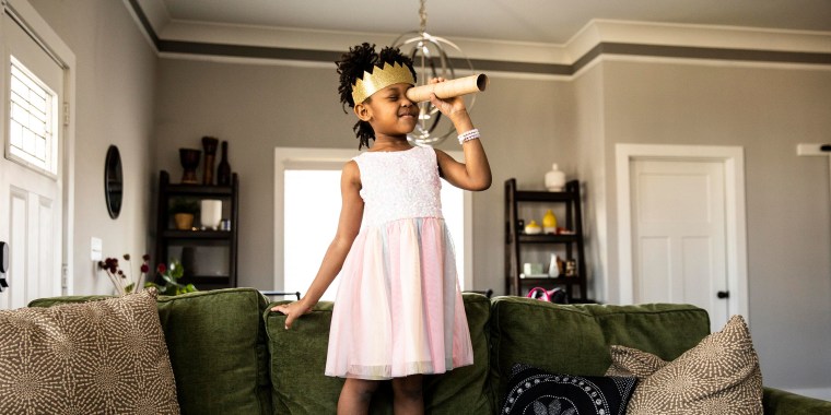 Young girl wearing homemade crown and looking through homemade telescope