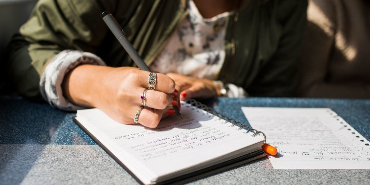 Midsection of businesswoman writing on diary in train