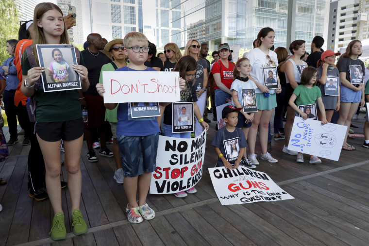 Children hold signs and photos of the Uvalde, Texas school shooting victims