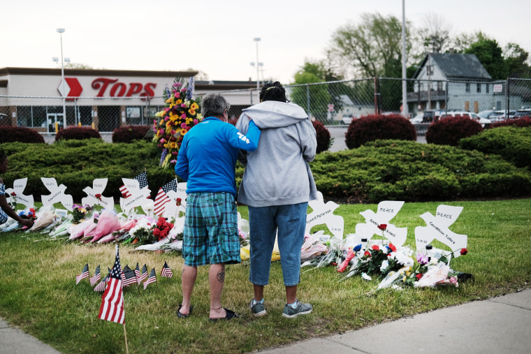 Image:  People gather at a memorial for the shooting victims outside of Tops market in Buffalo, N.Y., on May 20, 2022.