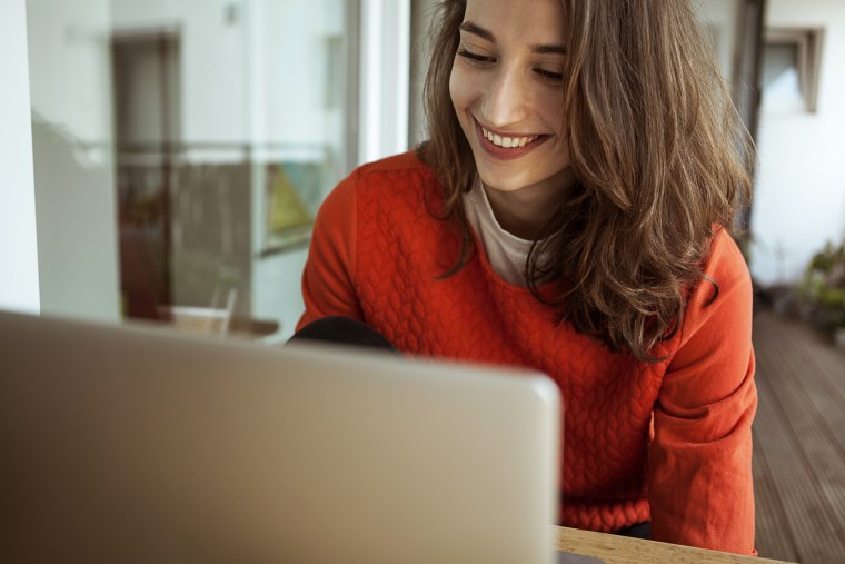 Smiling young woman using laptop on balcony