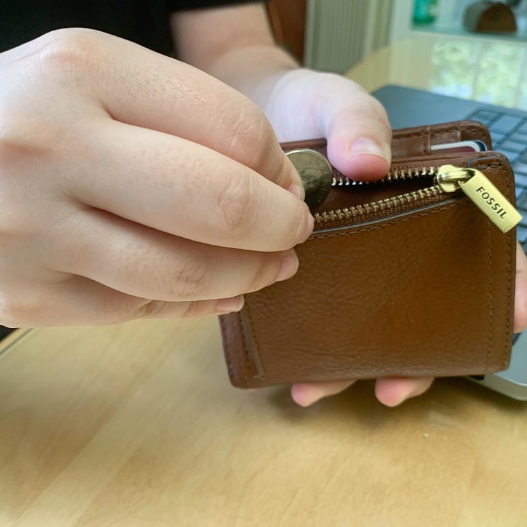 Image of someone adding change to the Logan Small RFID Bifold wallet