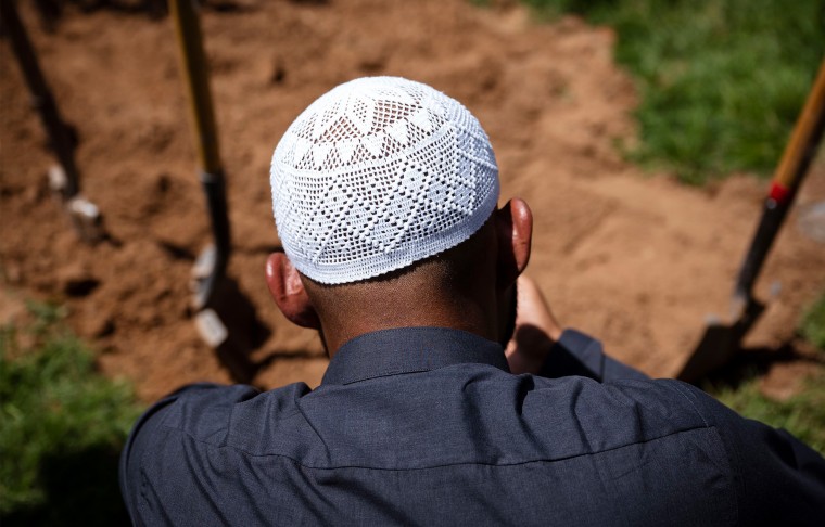 Image: A man praying over the grave of Muhammad Afzaal Hussain.