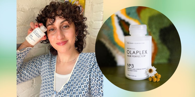 Woman holding up Olaplex No. 3 and a bottle of No. 3 siting on a counter.