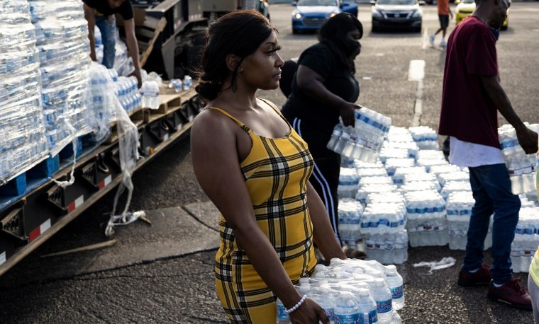 out cases of bottled water at a Mississippi Rapid Response Coalition distri...