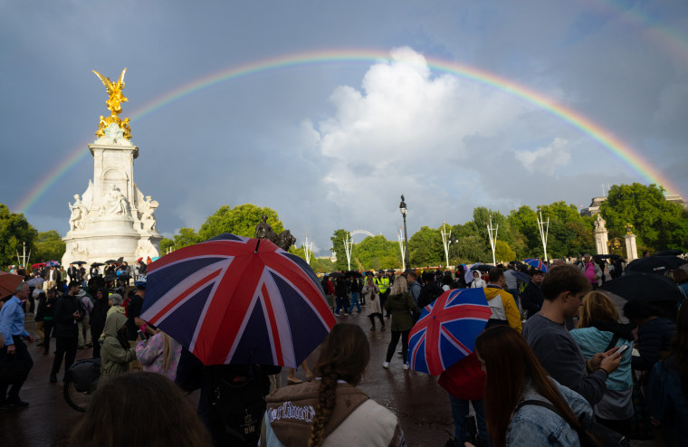 A man holds a Union flag umbrella as a rainbow is seen outside of Buckingham Palace on September 08, 2022 in London, England.