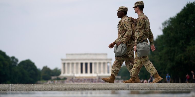 Image: Two members of the National Guard walk past at the World War II Memorial.