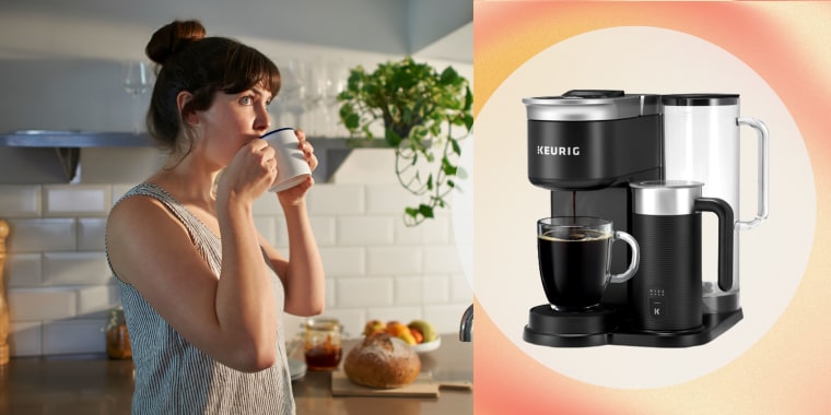 A woman standing in her kitchen drinks from a mug and the Keurig Cafe