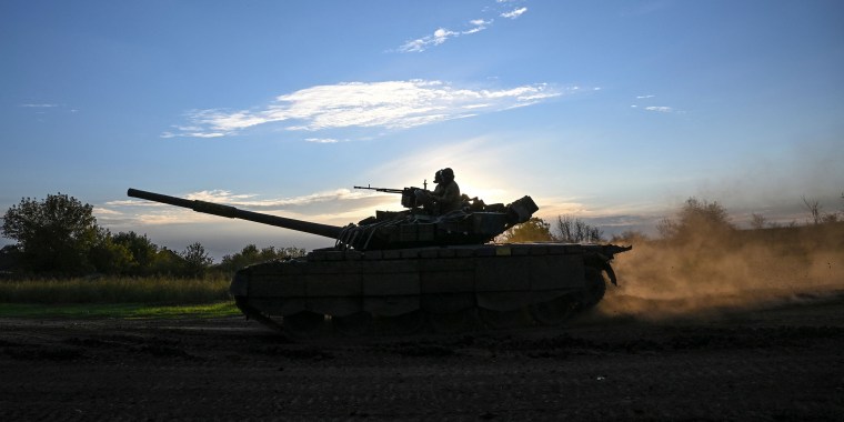 Image: Soldiers riding a tank.