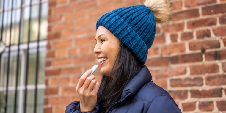 Woman outdoors putting on lip balm