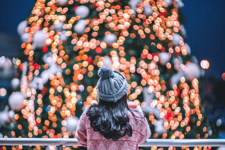 A woman looks at a Christmas tree.