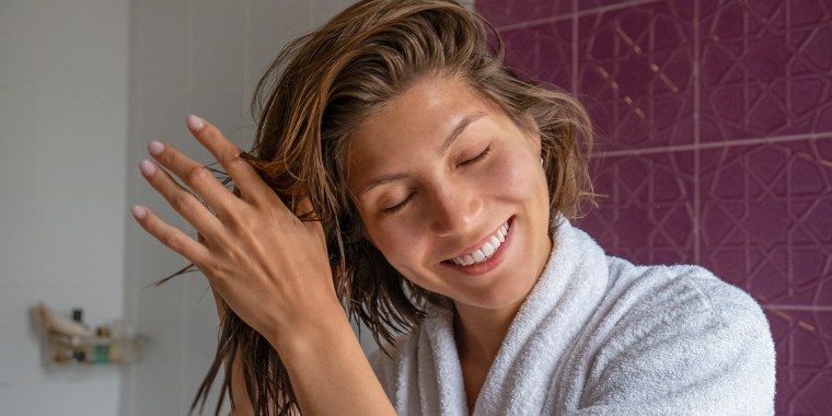 Woman in bathroom rubbing her hair