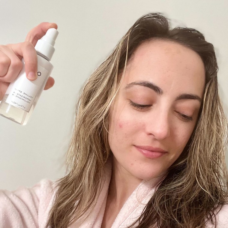 Woman spraying Ouai Spray in her hair