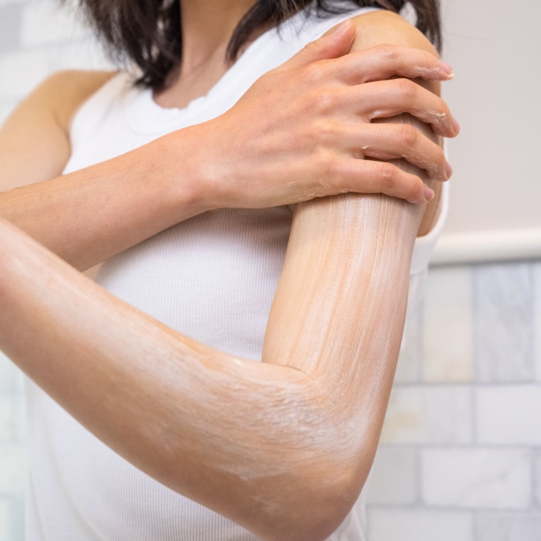 Woman rubbing lotion on her arm
