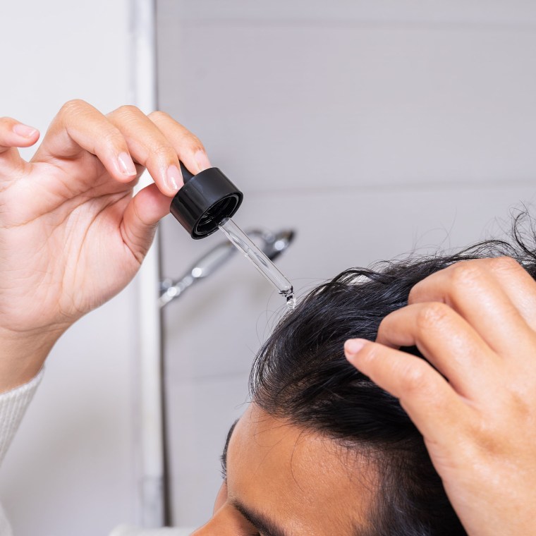 Woman putting serum in her hair