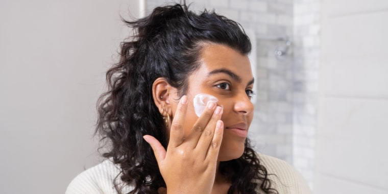 Woman putting cream on her cheek