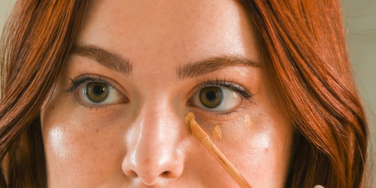 Woman looking in the mirror with Hydrating concealers