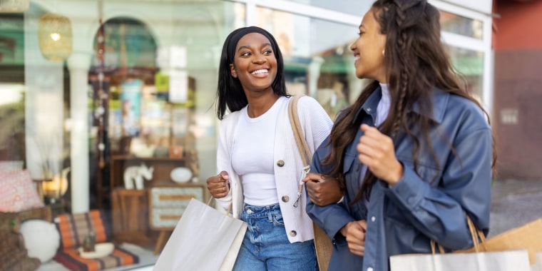Two women friends with shopping bags walking in the city - stock photo