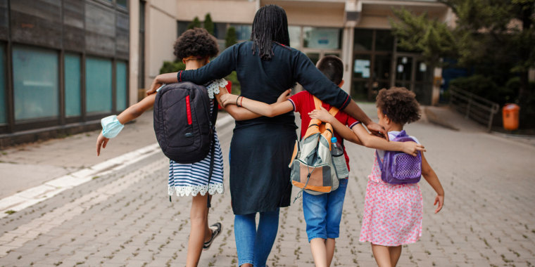 Black woman taking three kids to school