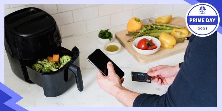Man in kitchen shopping on his phone, while using an air fryer