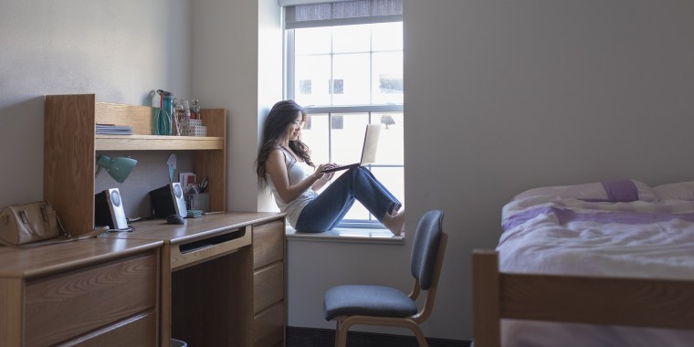 Young woman college student in her dorm room with laptop