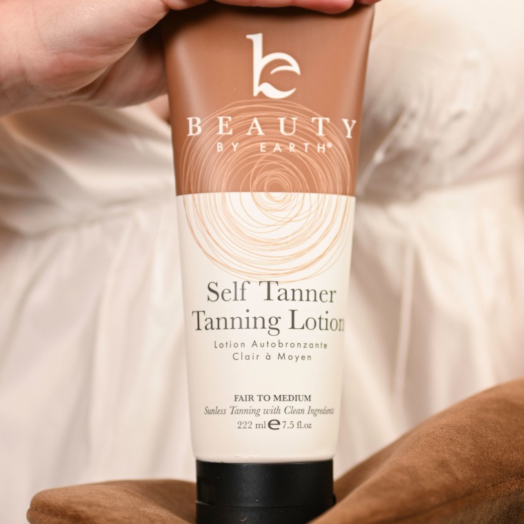 Hand holding a closed bottle of self-tanning lotion
