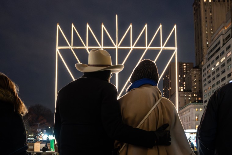 A gathering in Manhattan around the \"World's Largest Menorah\" on Thursday's first night of Hanukkah. The menorah is more than 30-feet tall and weighs some four thousand pounds. The holiday taking-on special significance this year given the war in Israel,