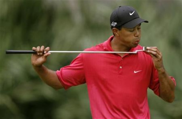 Tiger Woods blows on his putter on the 10th hole during final round play of the Tournament Players Championship in Ponte Vedra